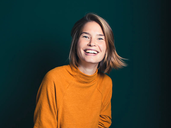 Picture of Carmen Zahno in an orange sweater on a green background